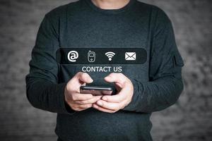 homme d'affaires utilisant un smartphone et tactile sur les icônes de contact de l'écran virtuel, adresse, téléphone, wifi, e-mail, contactez-nous et les gens de la hotline de support client se connectent. photo