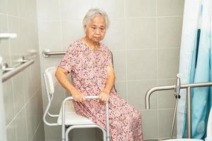 une femme âgée asiatique patiente utilise la sécurité de la poignée de la salle de bain des toilettes dans l'hôpital de soins infirmiers, concept médical fort et sain. photo