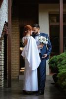 mariée en robe blanche avec un bouquet et le marié en costume bleu photo