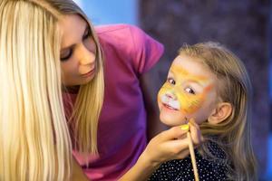 femme peignant le visage d'une petite fille photo