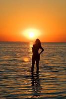 silhouette de la jeune femme sur un golfe au coucher du soleil photo