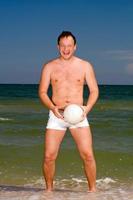 jeune homme tenant un ballon sur la plage photo
