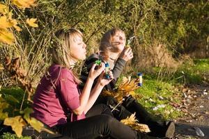 deux jeunes femmes de beauté démarrent une bulle de savon dans le parc photo