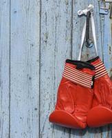 gants de boxe en cuir rouge accrochés à un vieux mur en bois bleu photo