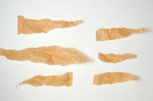 Morceaux bruns déchirés de papier parchemin sur un fond blanc photo