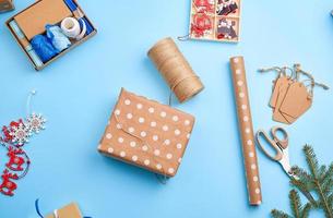 emballer les boîtes dans du papier brun festif, à côté du décor de la boîte à bagages sur fond bleu photo