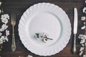 assiette blanche avec une fourchette et un couteau sur une surface en bois marron