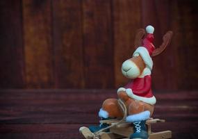 cerf jouet de noël en tenue de soirée assis sur un traîneau, un fond en bois marron photo