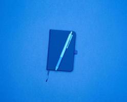 cahier fermé et stylo bleu sur fond coloré photo