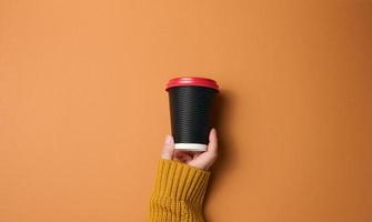 main tenir une tasse de papier carton brun pour le café. vaisselle écologique photo