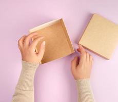 fille ouvre une boîte carrée marron sur fond violet photo