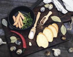 petites saucisses de viande avec une poêle et des œufs de caille crus photo