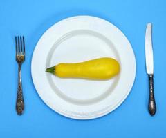 courge jaune crue dans une assiette en céramique blanche et une fourchette en fer avec un couteau photo