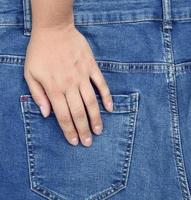 la main gauche repose sur la poche arrière d'un jean bleu photo