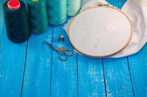 du fil turquoise avec le tissu dans le cadre à broder en bois pour les travaux d'aiguille photo