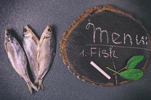 trois poissons séchés sur une surface noire photo