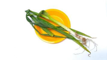 Légume poireau frais sur une plaque jaune isolé sur fond blanc photo