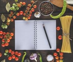 cahier vierge avec feuilles blanches, pâte longue crue et ingrédients pour la cuisine photo