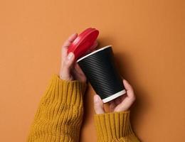 les mains tiennent une tasse de papier carton brun pour le café. vaisselle écologique photo