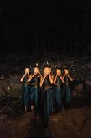 un groupe de femmes indonésiennes tenant et portant un masque en bois marron dans une jupe verte entre le rocher photo