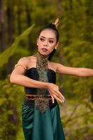 femme javanaise dansant devant les bois en costume vert tout en se maquillant et en jouant photo