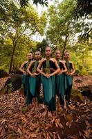 un plan large d'une femme asiatique debout ensemble dans la forêt tout en portant un costume de danse verte avec des feuilles mortes photo