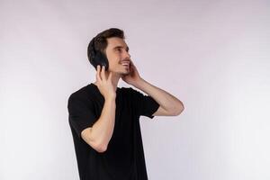 portrait d'un jeune homme heureux portant un casque et écouter de la musique sur fond blanc photo