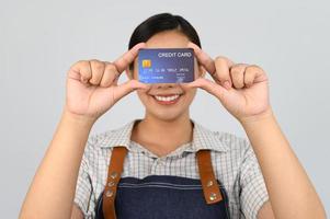 portrait de jeune femme asiatique en uniforme de serveuse pose avec carte de crédit photo