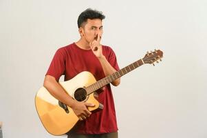 portrait de jeune homme asiatique en t-shirt rouge avec une guitare acoustique isolé sur fond blanc photo