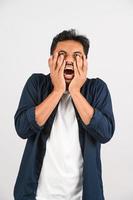 portrait de jeune homme asiatique déçu en chemise bleue agacé en colère dans un geste furieux isolé sur fond blanc photo