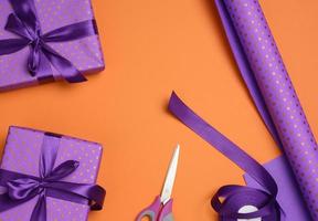 coffrets cadeaux attachés avec un ruban de soie violet sur fond orange, vue de dessus. photo