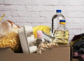 boîte en carton avec divers produits, fruits, pâtes, huile de tournesol dans une bouteille en plastique et conservation photo