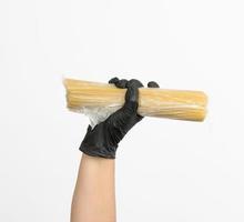 la main féminine dans un gant noir tient un sac transparent avec des spaghettis photo