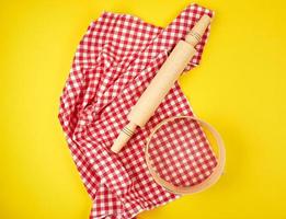 rouleau à pâtisserie en bois sur une serviette textile rouge et un tamis rond photo