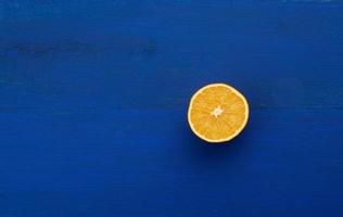 Orange juteuse à moitié mûre sur un fond de bois bleu foncé photo