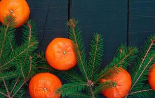 mandarines orange avec des branches d'épinette sur une surface en bois noire, vue de dessus photo