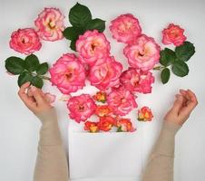 deux mains féminines et une enveloppe en papier avec des bourgeons de roses roses photo