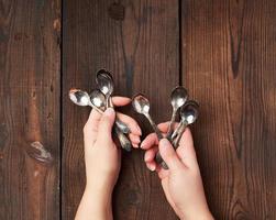 deux mains féminines tenant un ensemble de petites cuillères à café en métal photo