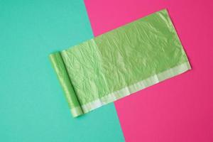 sac en plastique transparent vert pour les ordures sur un fond coloré photo