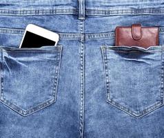 portefeuille en cuir marron et un smartphone blanc avec un écran noir vide dans la poche arrière photo