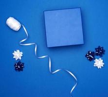 boîte cadeau carrée en carton, arcs, rubans pour l'emballage sur fond bleu foncé photo