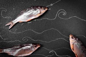 trois séchés dans le bélier de poisson salé sur la surface noire photo