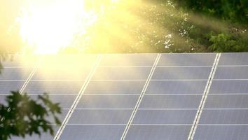 panneau solaire sur le toit de la maison dans les rayons du soleil éclatant parmi les arbres photo