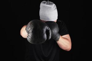 jeune homme se tient dans un rack de boxe, portant de très vieux gants de boxe marron vintage photo