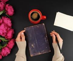 deux mains féminines, sur la table un bouquet de pivoines rouges photo