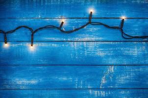 guirlande électrique avec des lumières rougeoyantes sur un fond en bois bleu photo