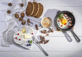 fromage, une tasse de café et une poêle en fonte noire avec un œuf au plat photo