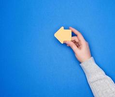 la main tient un autocollant en papier orange sous la forme d'un pointeur de flèche photo