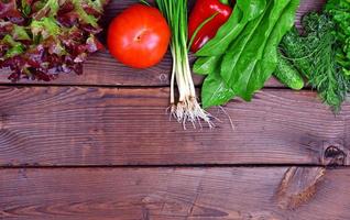 Légumes frais de tomate, concombres et oignons verts sur un fond en bois brun photo