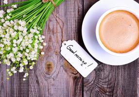 tasse de cappuccino et un bouquet de lys blancs de la vallée photo